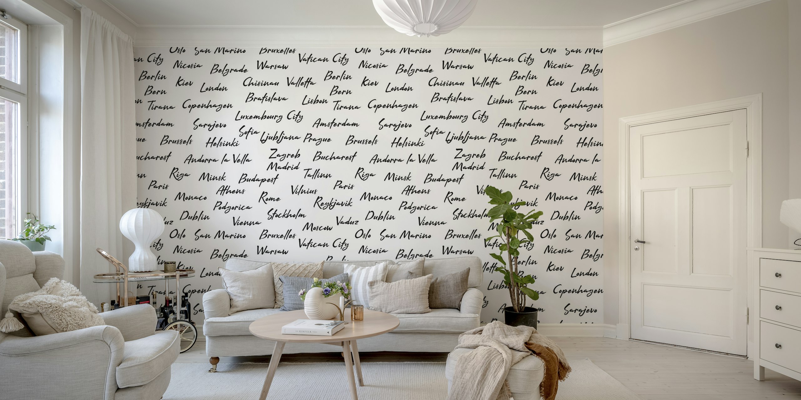 Black and white wall mural featuring handwritten names of European capital cities