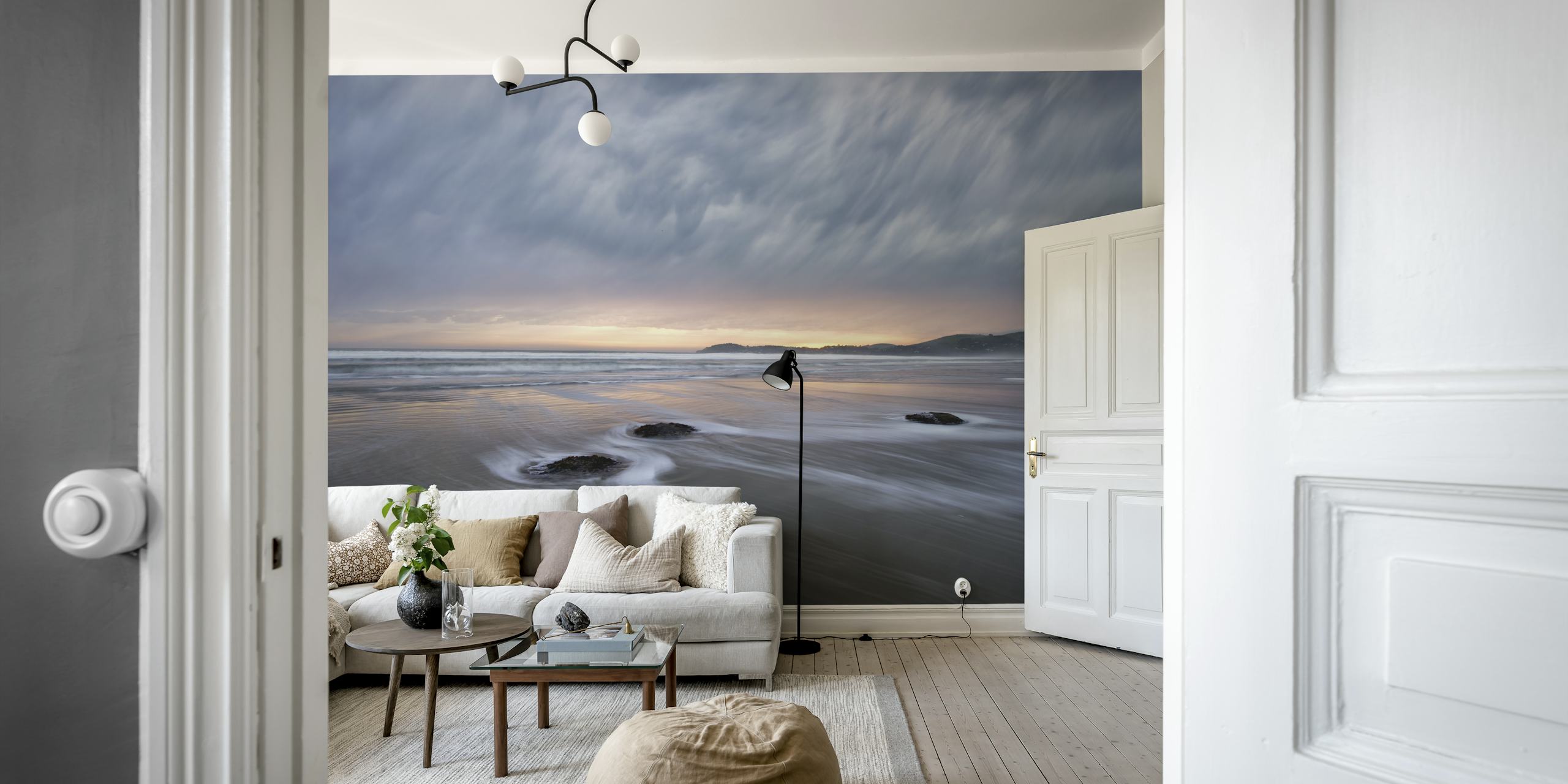 Beach landscape with flowing waves, gray clouds and soft sunset hues wallpaper