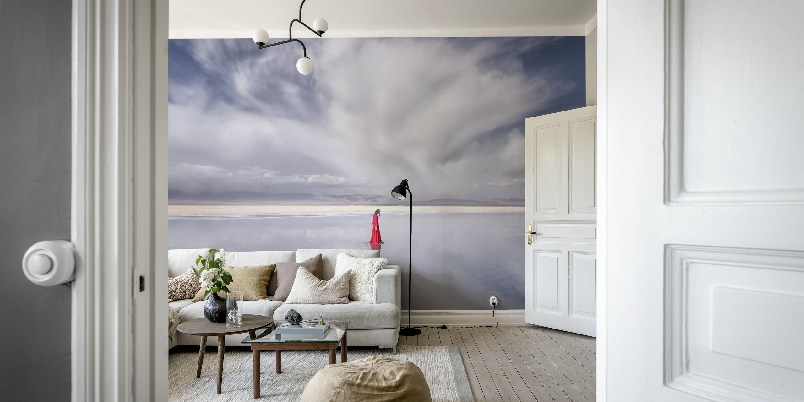 En ensam kvinna i röd klänning som står mot en fridfull bakgrund av himmel och vatten som blandas vid horisonten